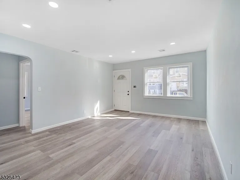 Renovated living room at 65 Rutgers Street with new light oak floors and a front entry door