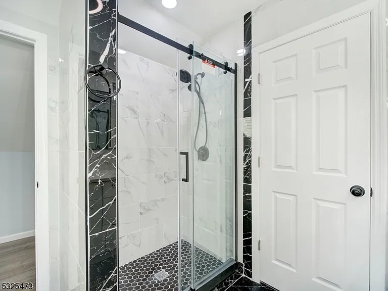 Renovated bathroom at 65 Rutgers Street with black-and-white marble tile and a frameless glass shower