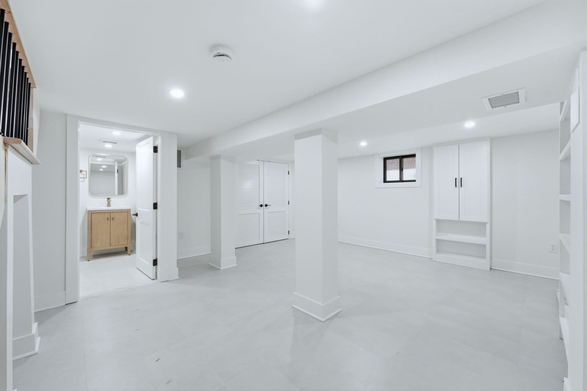 Finished basement living area with custom built-in shelving and an adjoining powder room