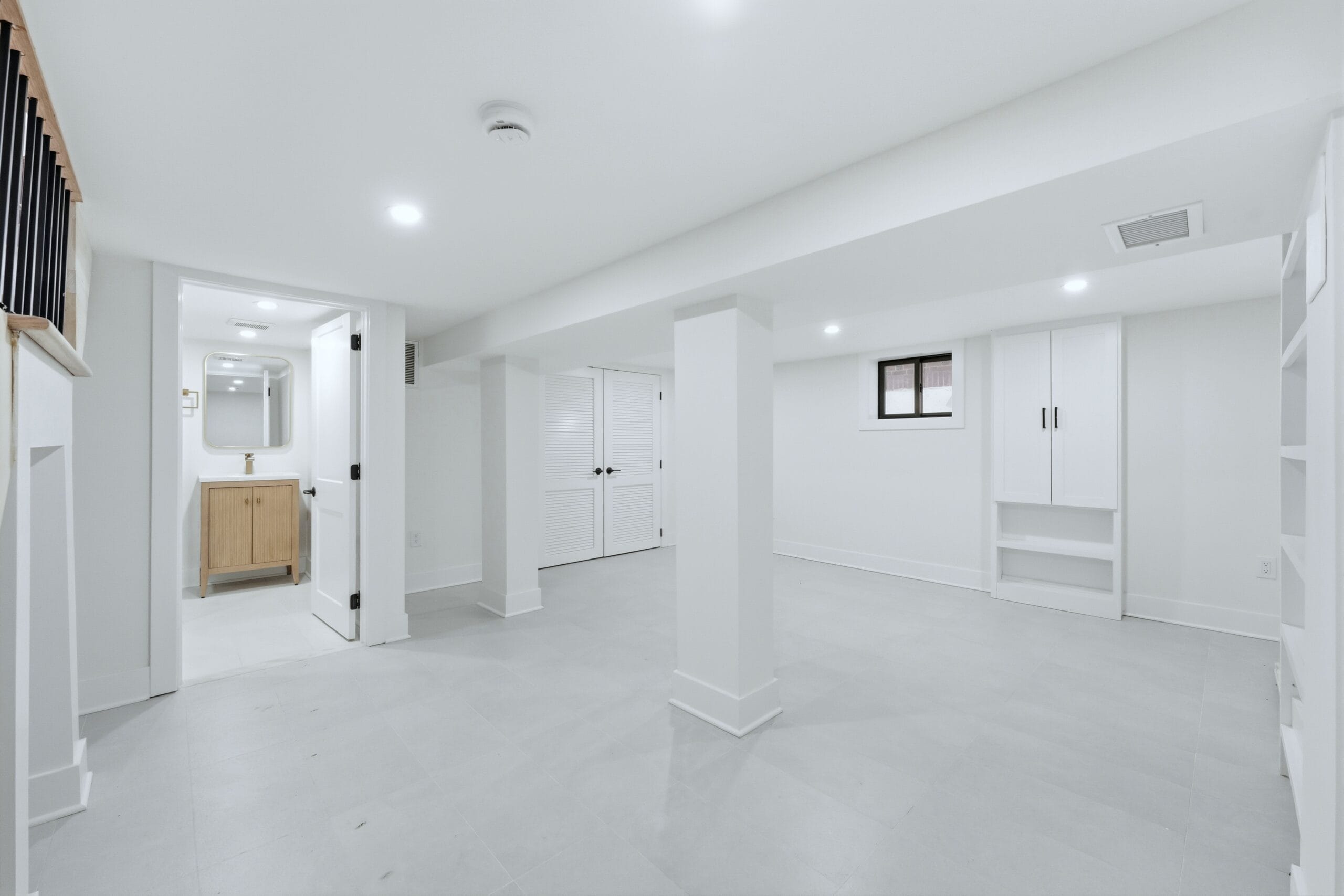 Finished basement living area with custom built-in shelving and an adjoining powder room