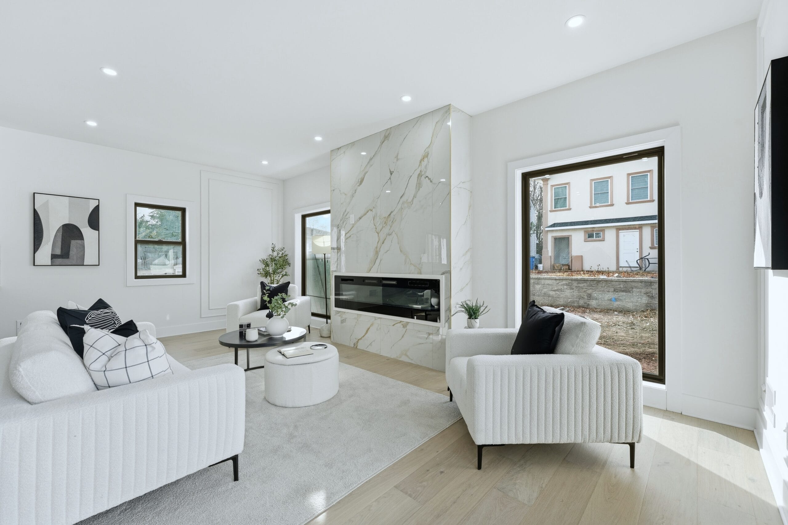 Sunlit living room with a full-height Calacatta marble fireplace surround and white bouclé seating