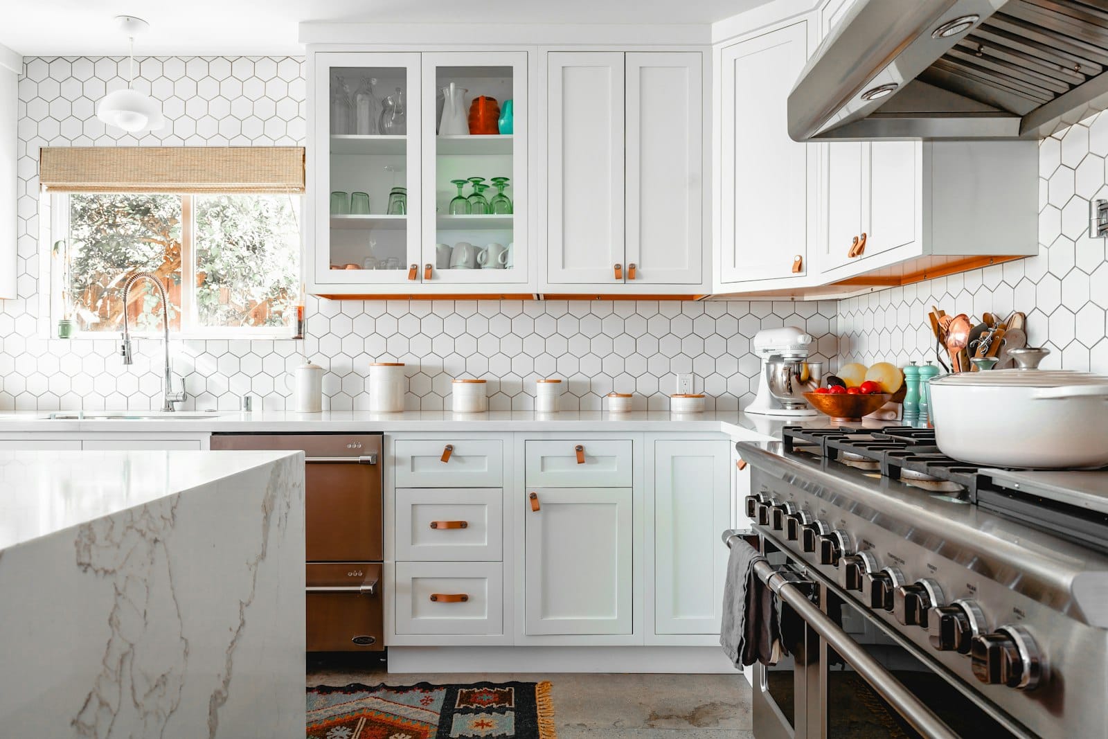 Renovated kitchen with white hex-tile backsplash and a marble waterfall island