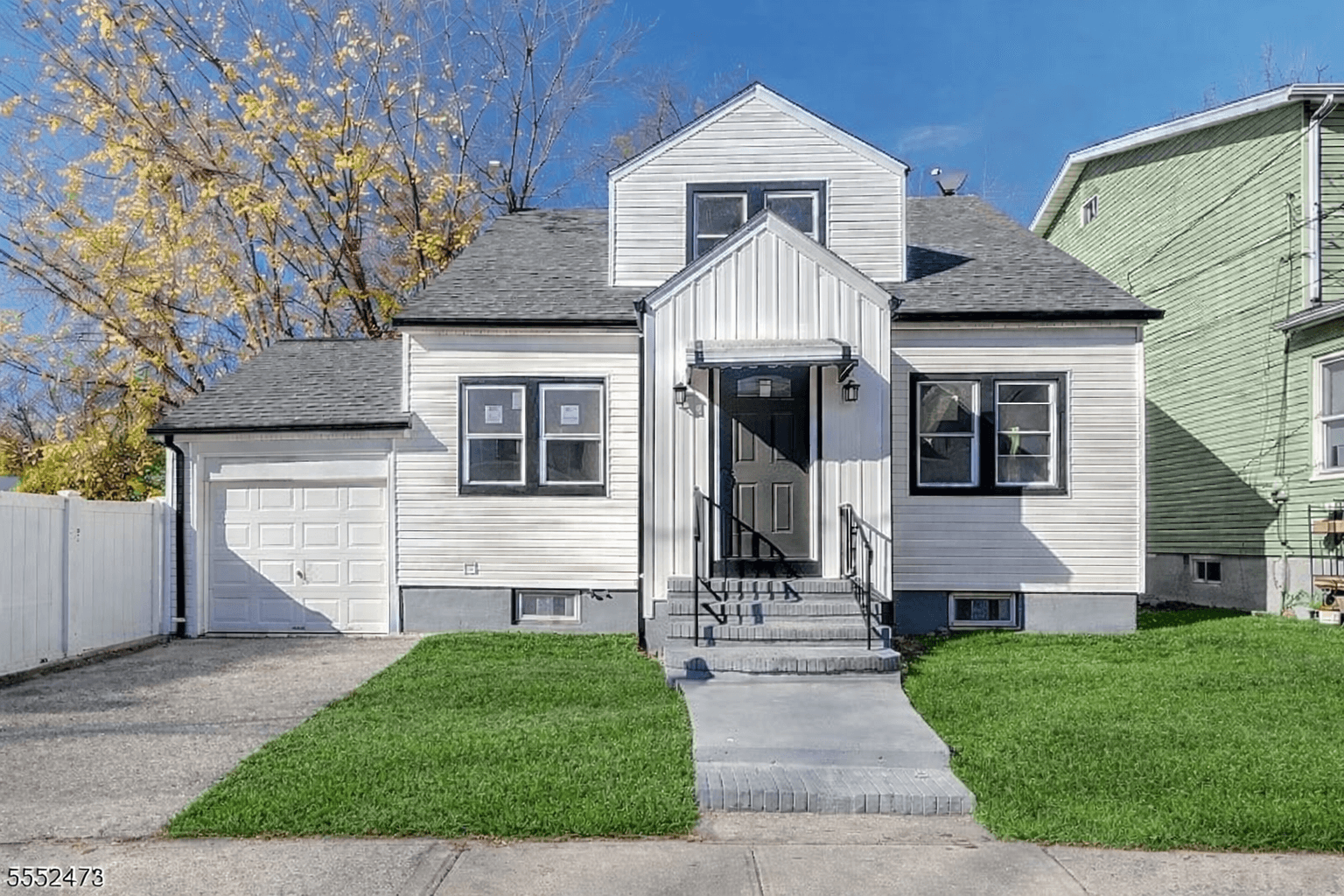 Front exterior of 65 Rutgers Street — a renovated white Cape Cod home with a front dormer and attached garage