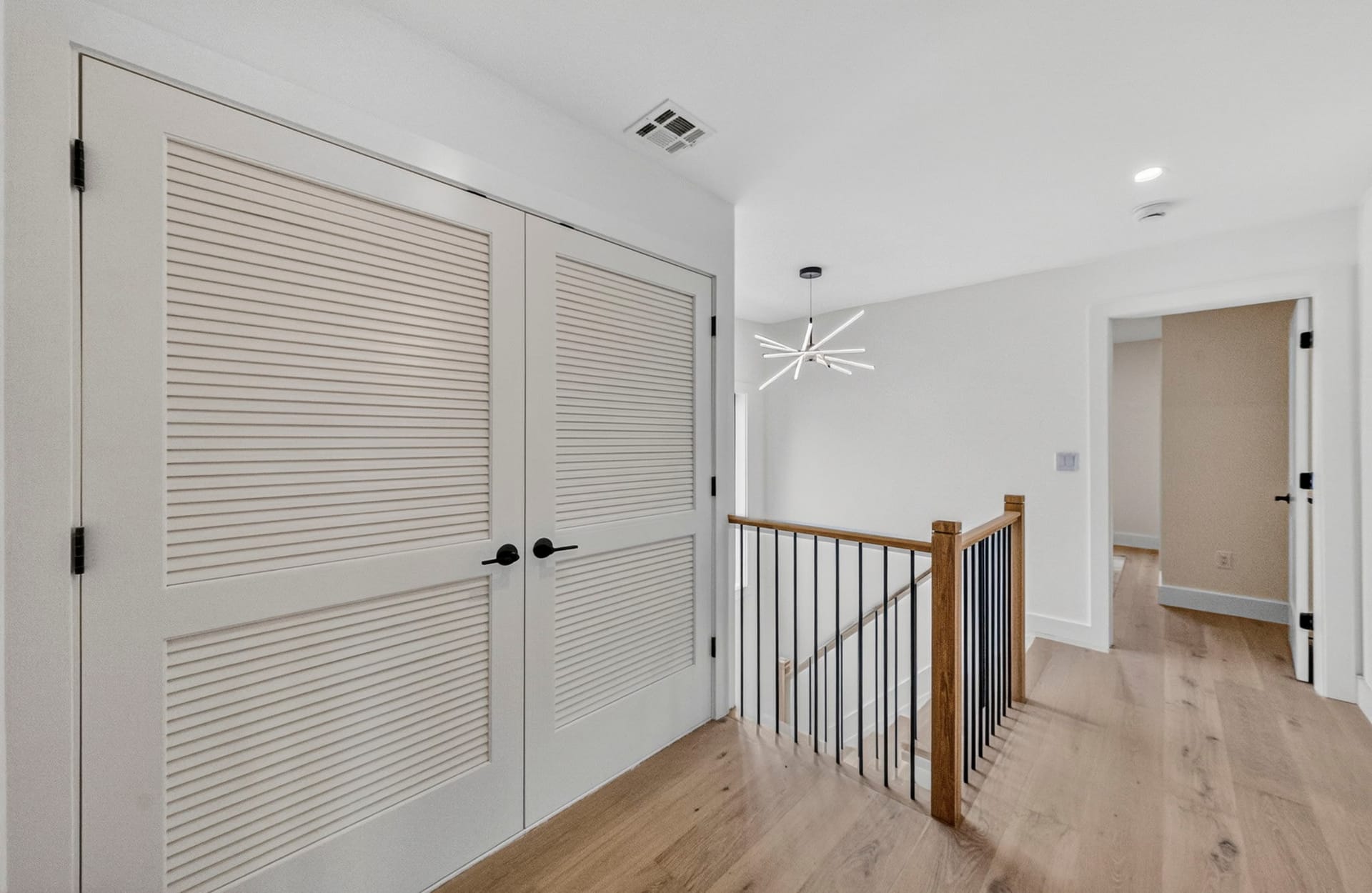 Upstairs hallway with louvered linen closet doors and the staircase landing