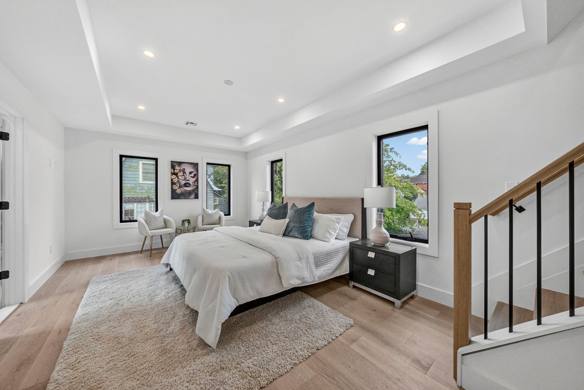 Primary bedroom with a tray ceiling and open stairwell