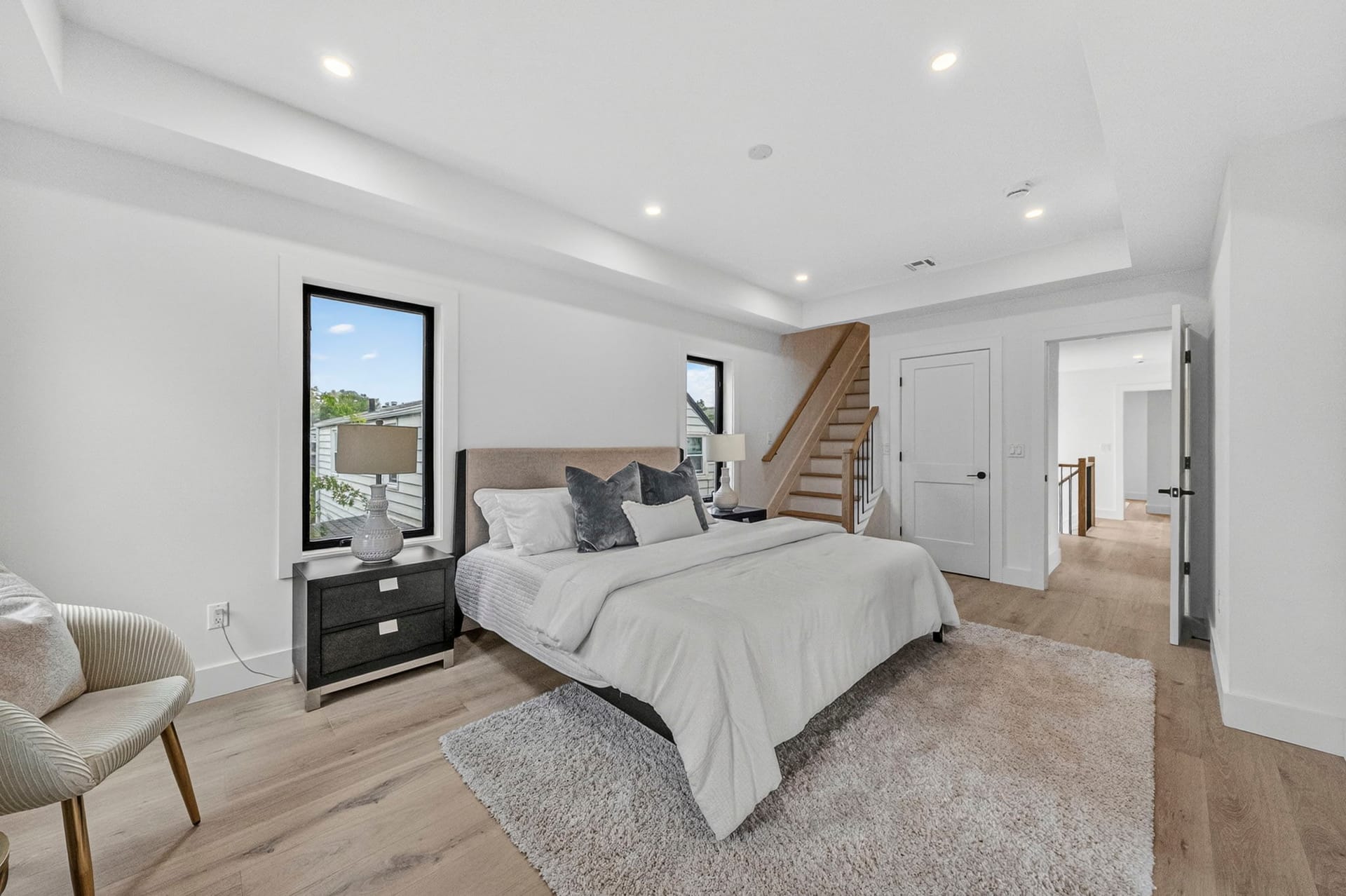 Primary bedroom with a tray ceiling, dark wood nightstand, and accent chair