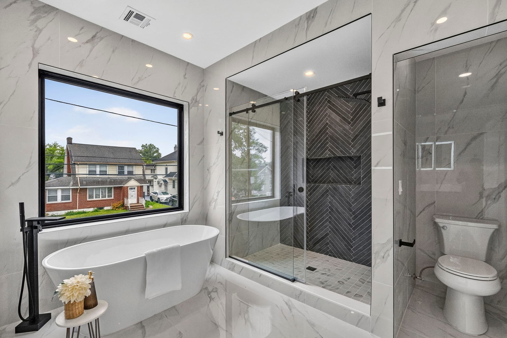 Primary bathroom with a freestanding tub beside a glass shower with herringbone tile