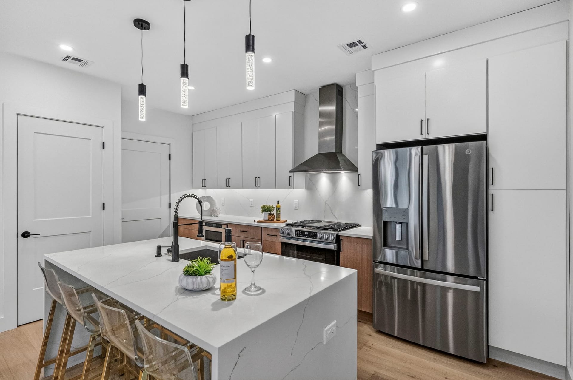 Kitchen with white cabinetry, a waterfall-edge island, and stainless appliances