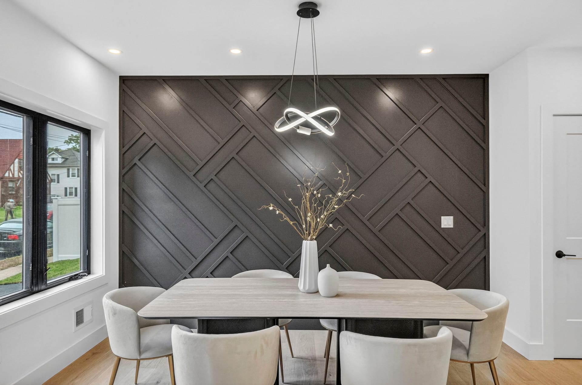 Dining area with a dark geometric accent wall and pendant lighting