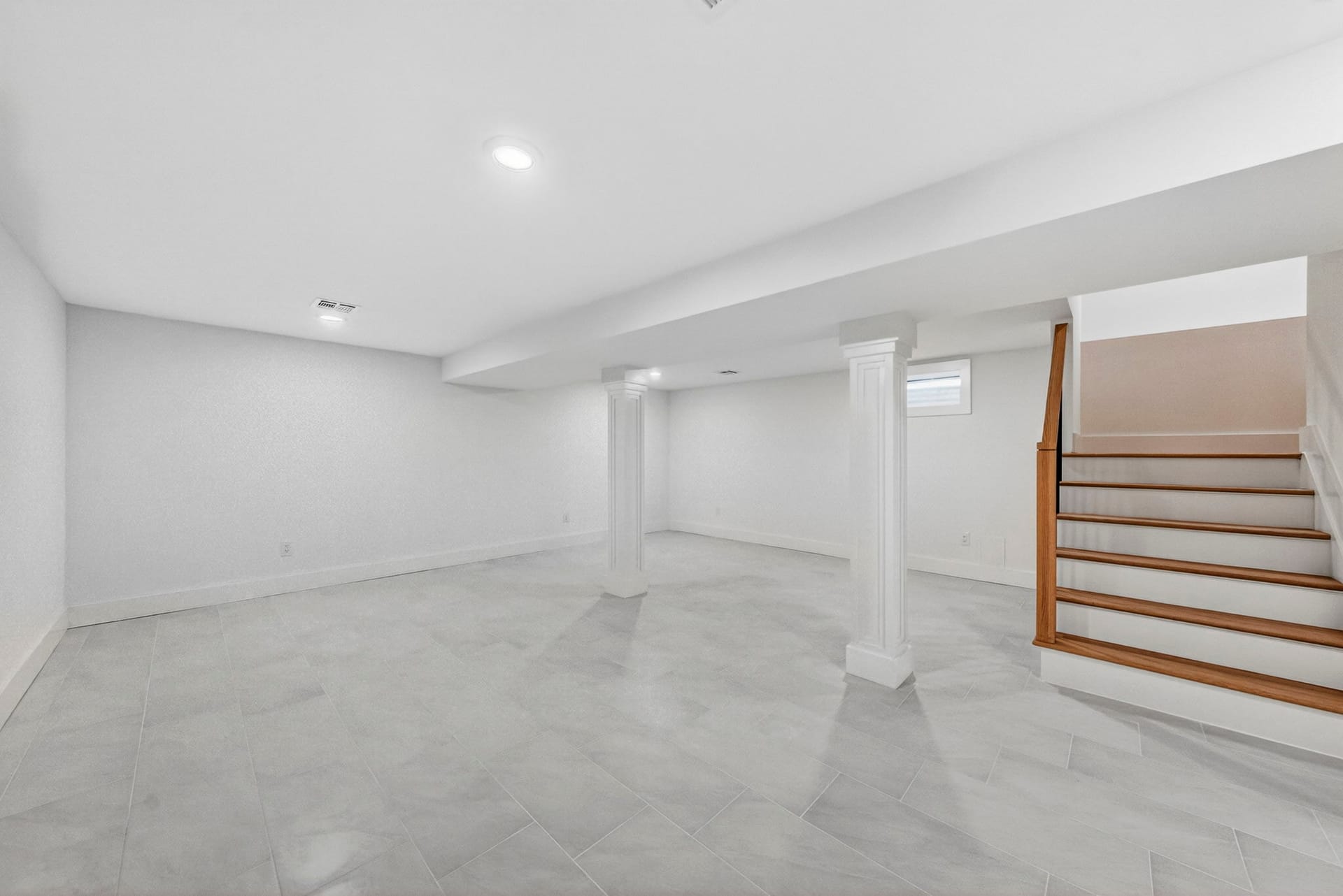 Basement recreation room with a polished floor and decorative columns