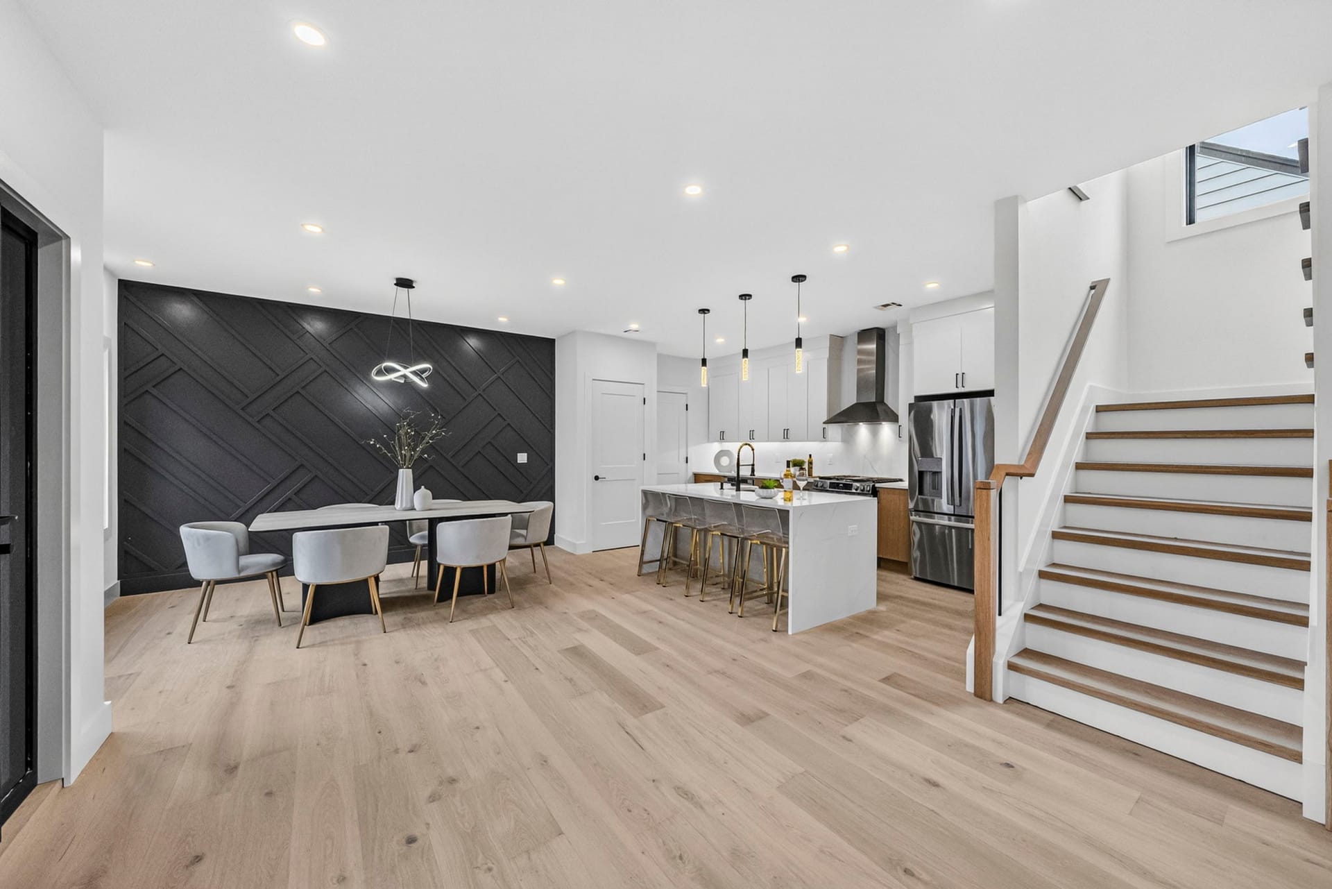 Open living and dining area with the staircase and dark accent wall