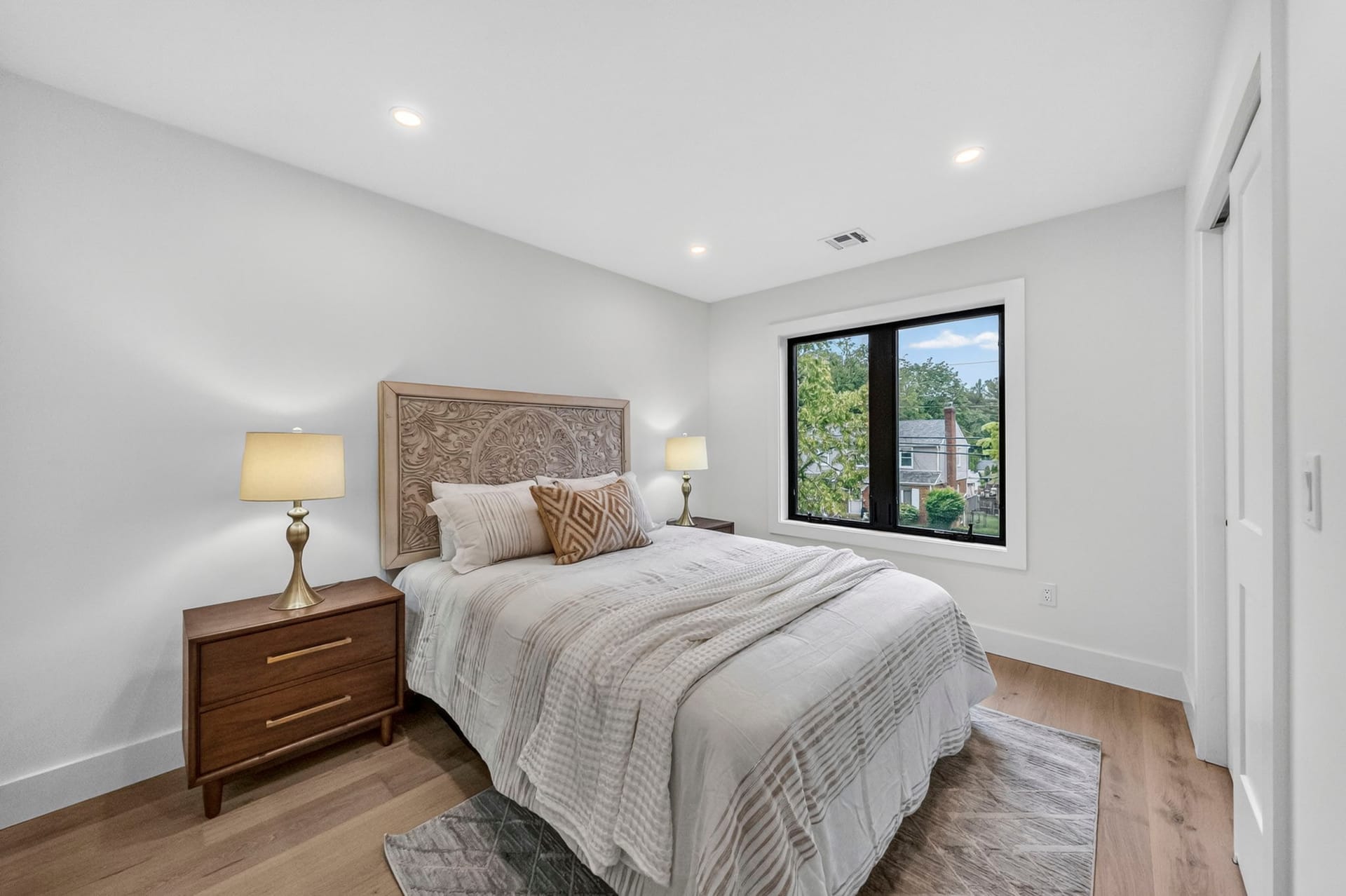 Bedroom with a wood headboard and a street-facing window